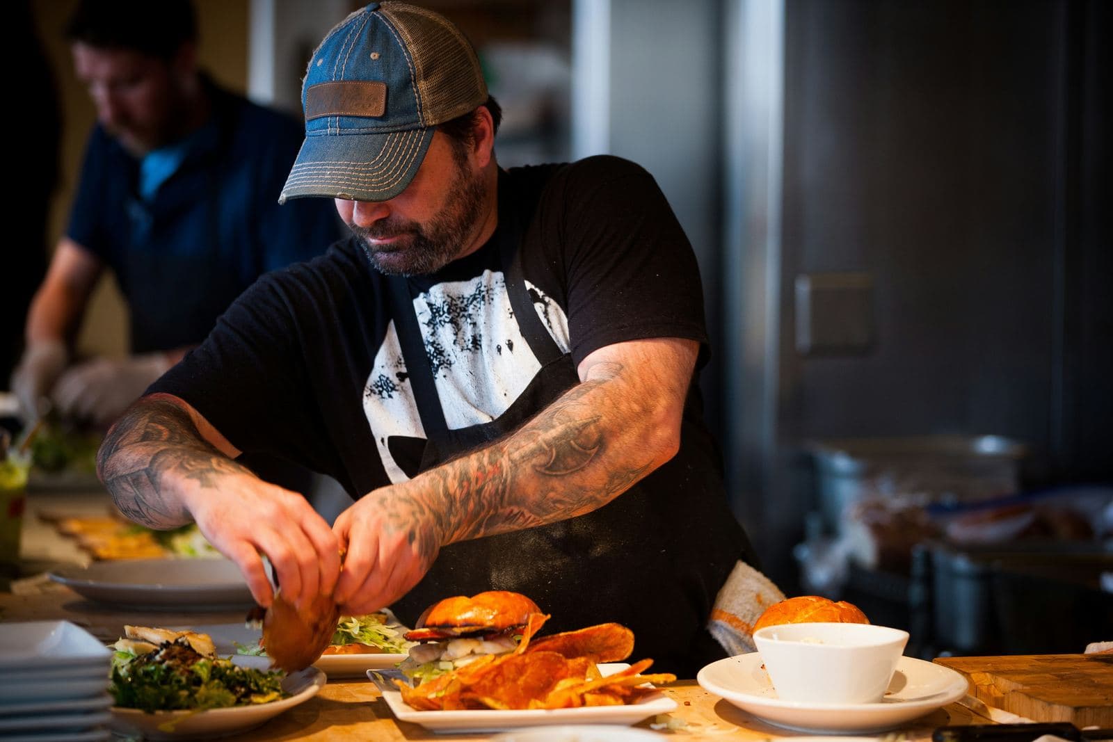 A restaurant owner plating dishes at the pass